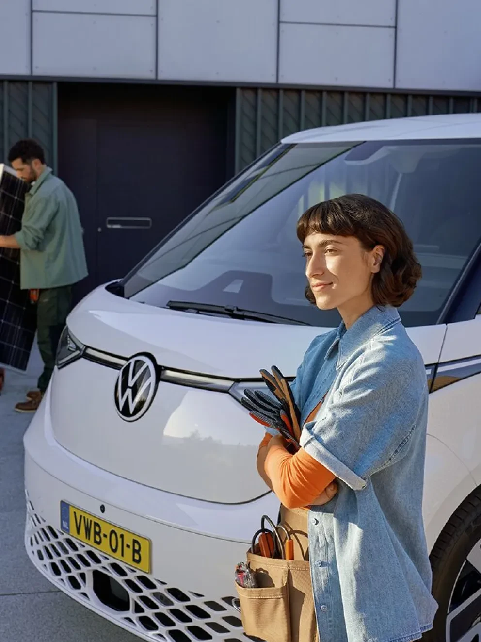 Vrouw die voor een witte Volkswagen ID. Buzz