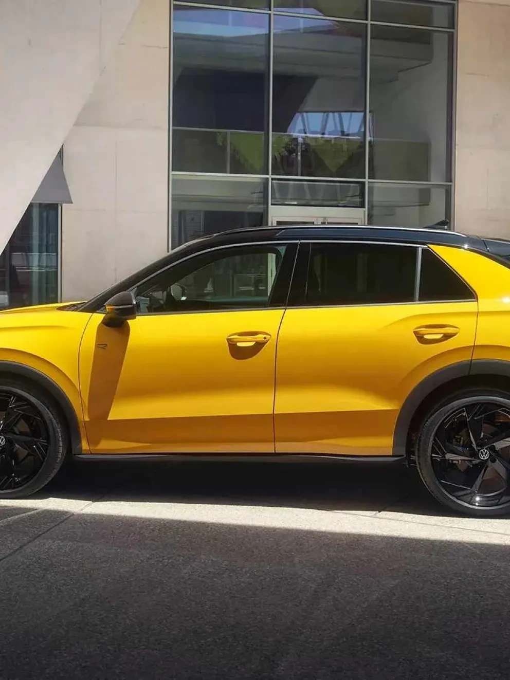 Man die voor een gele Volkswagen T-Roc langs loopt
