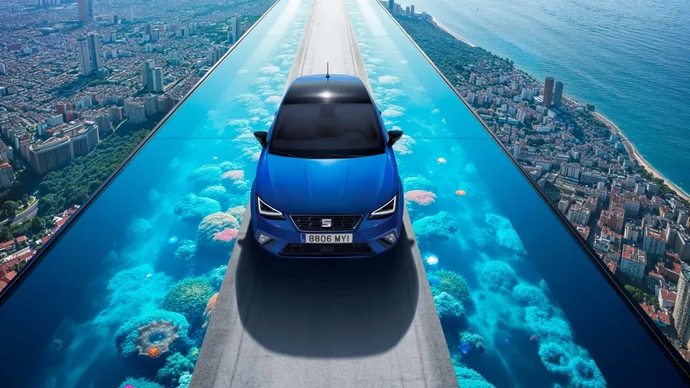 Blauwe SEAT Ibiza rijdend op een weg over een aquarium