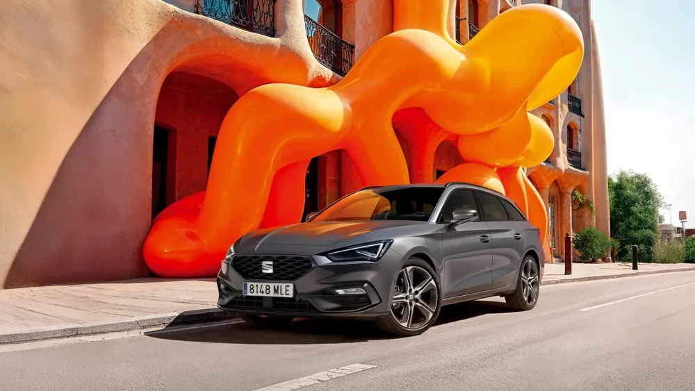 Donkergrijze SEAT Leon voor een gebouw