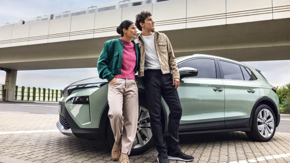 Man en vrouw die tegen een lichtgroene Škoda Elroq leunen