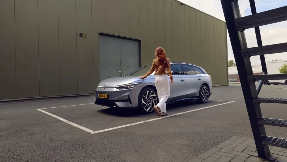 Vrouw loopt langs zilvergrijze Volkswagen ID.7 Tourer