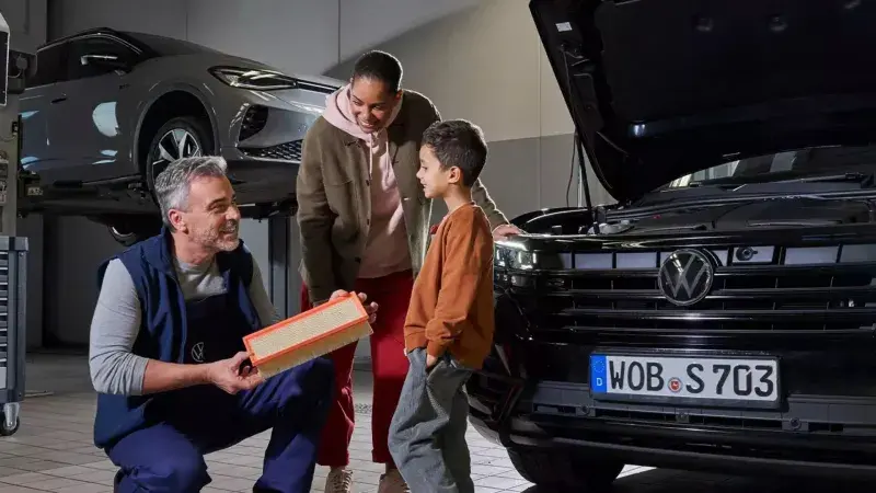Volkswagen monteur laat airco filter zien aan moeder en zoon in de werkplaats