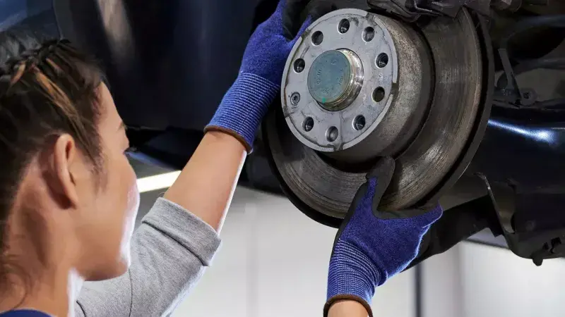 Volkswagen monteur sleutelt aan de schijfrem van een Volkswagen in de werkplaats